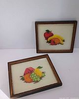 Front view showing both framed needlepoint fruit pictures