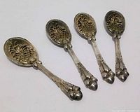 Four ornate silverplate dessert spoons front view showing pineapple design and acorn handles