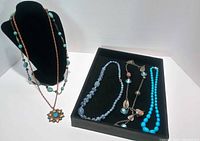 All five necklaces arranged on display stand and tray