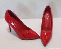 Side and top view of both pumps showing red patent finish and pointed toe