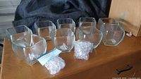 Nine clear glass square bowls and bags of acrylic ice on wooden surface