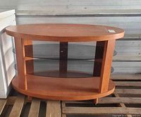 Front view of oval cherry console table showing top, two glass shelves, legs