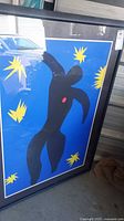Full view of framed abstract figure print leaning against wall