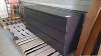 Front angled view of entire dark brown 6-drawer dresser on pallet