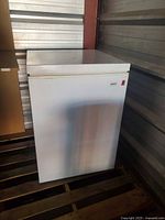 Front and side view of white Kenmore chest freezer on pallet
