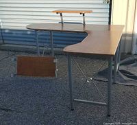 Full view of L-shaped desk showing monitor shelf, keyboard tray, metal frame, top surface