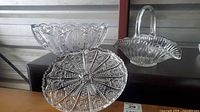 Three crystal bowls: handled basket, deep round, wide shallow starburst