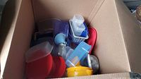 Box containing assorted plastic food storage containers, lids, glass bottle, mesh strainer