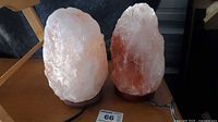 Two Himalayan salt lamps on wooden bases with cords visible