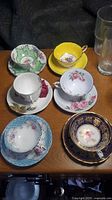 Six assorted bone china cup and saucer pairs on table