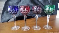 Front view of four colored cut-to-clear crystal goblets on table