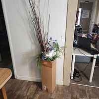 Full view of tall faux floral arrangement in cardboard container