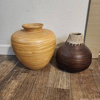 Light and dark faux wood vases side by side on floor