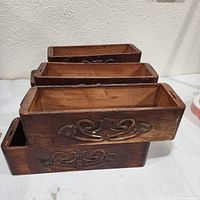 Four carved wooden boxes side view showing scrollwork fronts