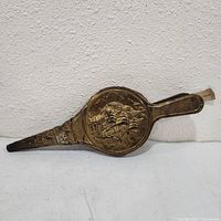 Full view of fireplace bellows showing brass-embossed ship motif and overall form