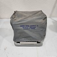 Typewriter covered by gray fabric dust cover