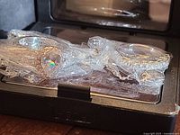 Two rings in plastic wrap inside display box showing halo ring and band ring