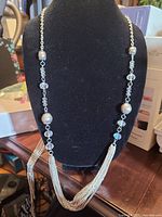Front view of full necklace on stand showing bead pattern and multi-strand chain drape