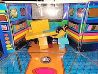 Interior view of open bridge playset with Captain Kirk figure seated at yellow console and blue chair, showing floor graphics and clear front panels