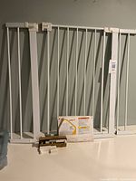 Full view of white metal baby gate with extensions and hardware