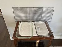 two glass baking dishes and two cooling racks displayed against wall