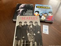 All three Beatles-related hardcovers laid out: Lennon biography, Illustrated Lyrics, Unseen Archives