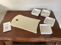 Cheese board and four square dishes displayed on table