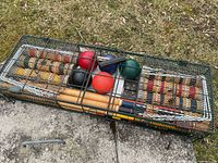 Full view of croquet set in metal carrier showing mallets, balls, stakes and wickets