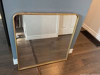 Front view of square gold framed mirror with rounded top corners