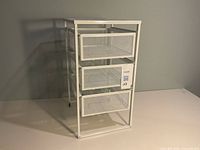 Front view of white metal frame with three mesh drawers