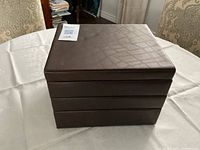 Closed brown four-tier jewelry box on table