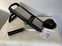 Entire mandoline slicer with food holder, blades case and lot tag visible