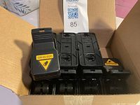 Cardboard box containing eight black plastic snap mouse traps, one positioned upright showing caution label