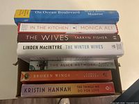 Stack of seven novels showing spines with titles and authors
