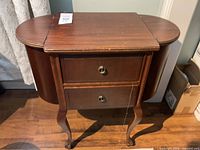 Front view of closed wooden sewing cabinet on cabriole legs