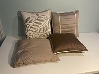 Four square pillows on tabletop showing designs and colors