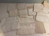 Group of 11 vintage white and ivory linens folded to show embroidery, lace and drawn-work