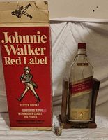 Bottle in cradle with shot glass beside and box