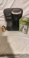 Front view of Keurig brewer, glass carafe and boxed cappuccino creamer