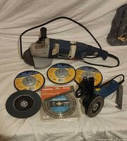 All items in lot: two blue angle grinders, five discs including sealed Makita blade