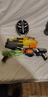 Group shot of three Nerf blasters and mask