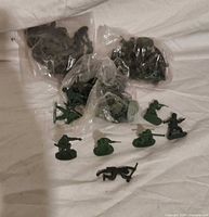 Bags of green plastic army men with several loose figures displayed