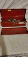 Open red toolbox with lid up and tray removed, showing assorted tools