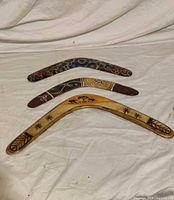 Three painted wooden boomerangs laid out