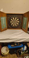 Cabinet open showing dartboard, chalk score panels and cork backing