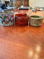 Three wide hinged cuffs side by side on table