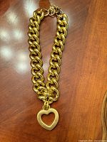 Full view of gold-plated curb link necklace with heart pendant and clasp visible