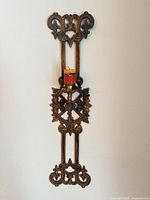 Full view of tall ornate gold-bronze wall sconce holding one candle