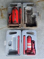 Four open plastic carry cases showing two bottle jacks and accessory handles