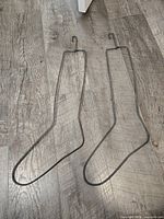 Two metal wire sock stretchers lying flat on floor showing full shape and hooks